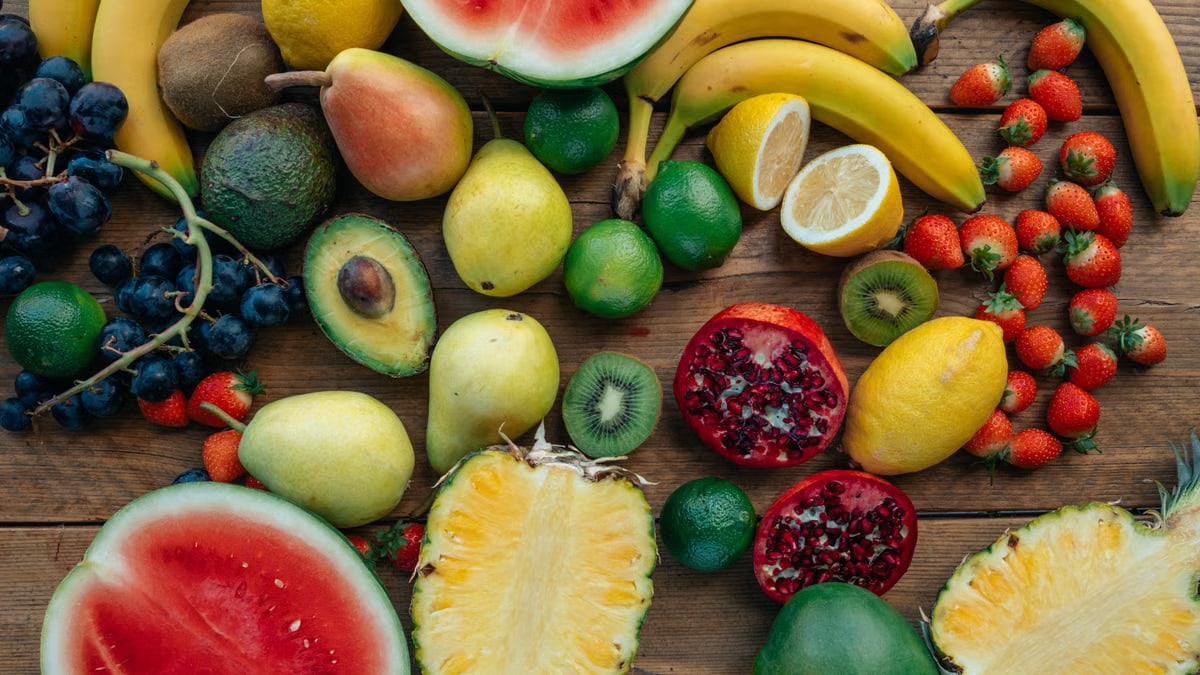 A colorful assortment of fresh fruits including bananas, strawberries, and watermelon arranged on a wooden table.